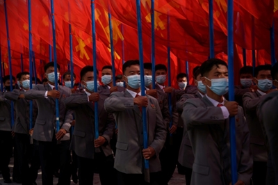 North Koreans rally wearing masks after military parade