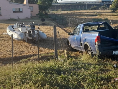 Bakkie met boot ploeg deur heining