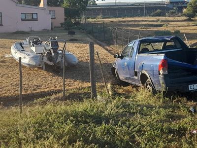 Bakkie met boot ploeg deur heining